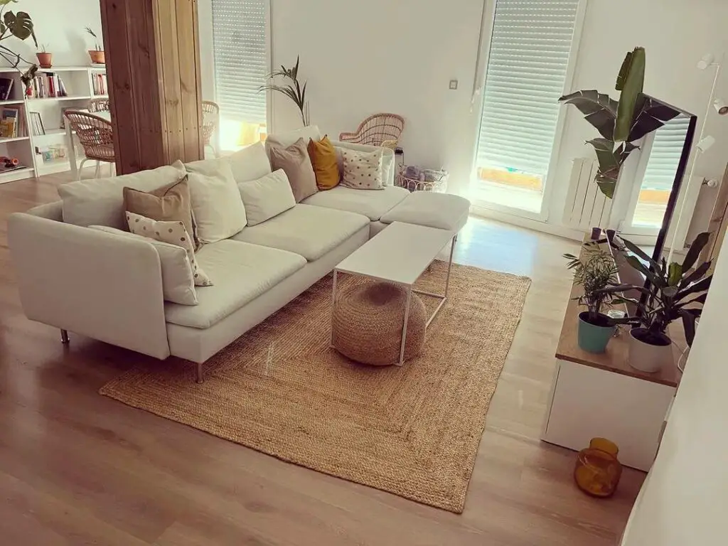 Salon de style moderne avec canapé avec chaise longue d'IKEA.Salon avec canapé blanc avec méridienne, tapis et bouffée en jute, table basse en métal blanc et plantes.Instagram @summerwindhomedecor