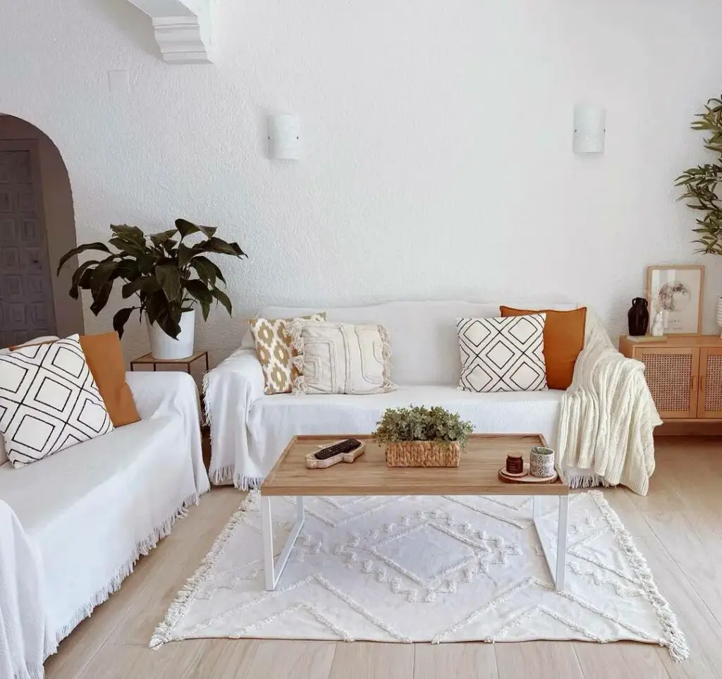 Salon méditerranéen rustique avec canapés IKEA EKTORP et couverture RÖNNBÄRSMAL.Séjour avec 2 canapés abrités avec couvertures et coussins de couleurs et motifs variés, une table basse en bois avec pieds en métal blanc et un tapis berbère blanc.Instagram @temple_home