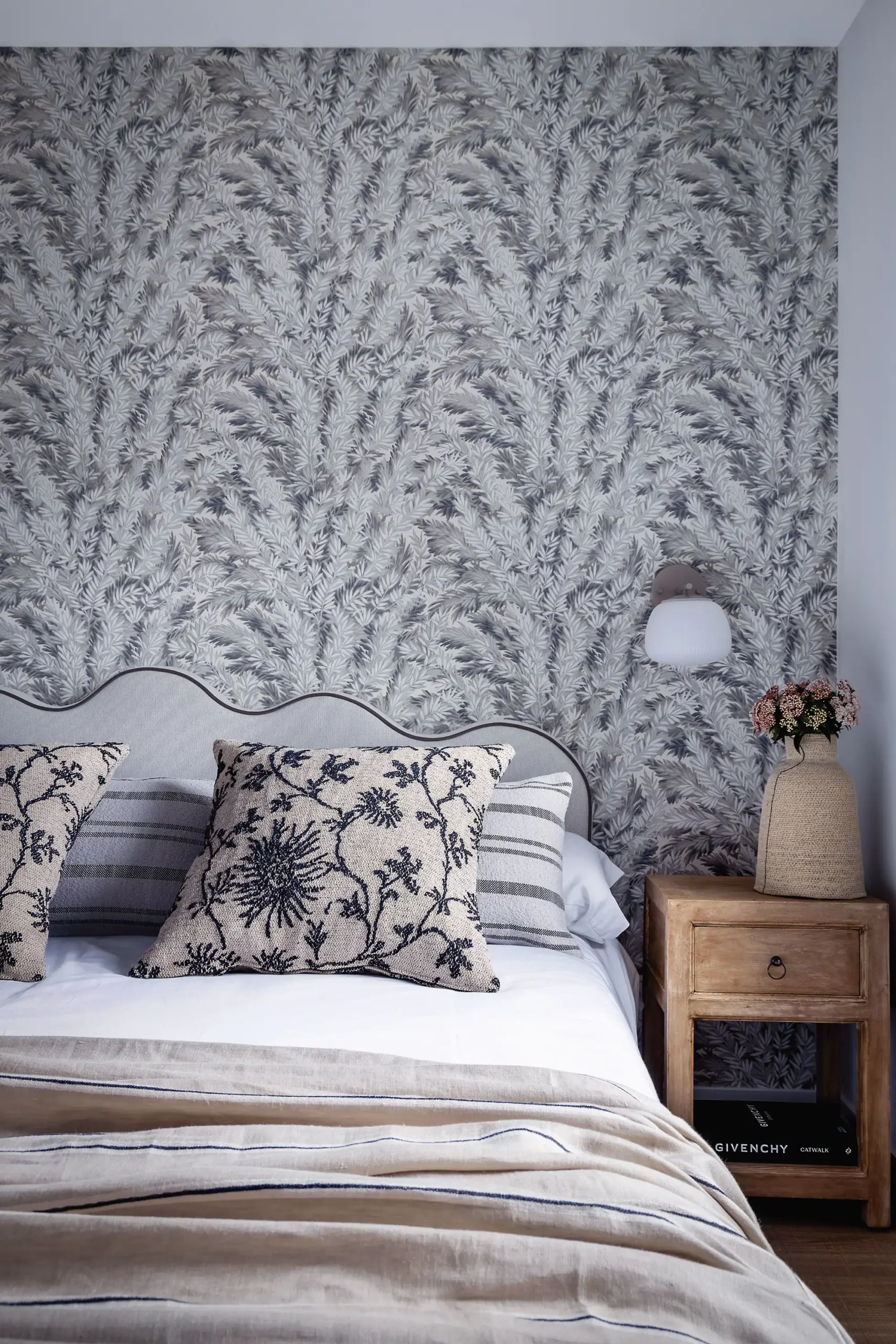 Petites appliques murales blanches dans une chambre avec papier peint fleuri