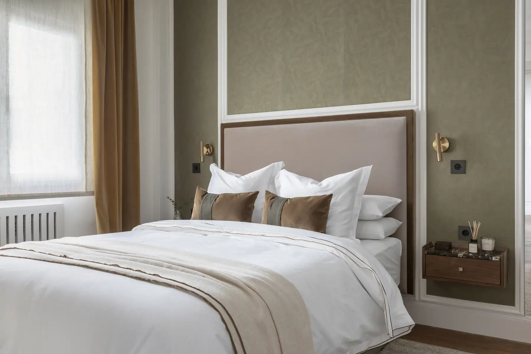 Appliques murales en laiton doré sur mur vert textile dans une chambre chaleureuse