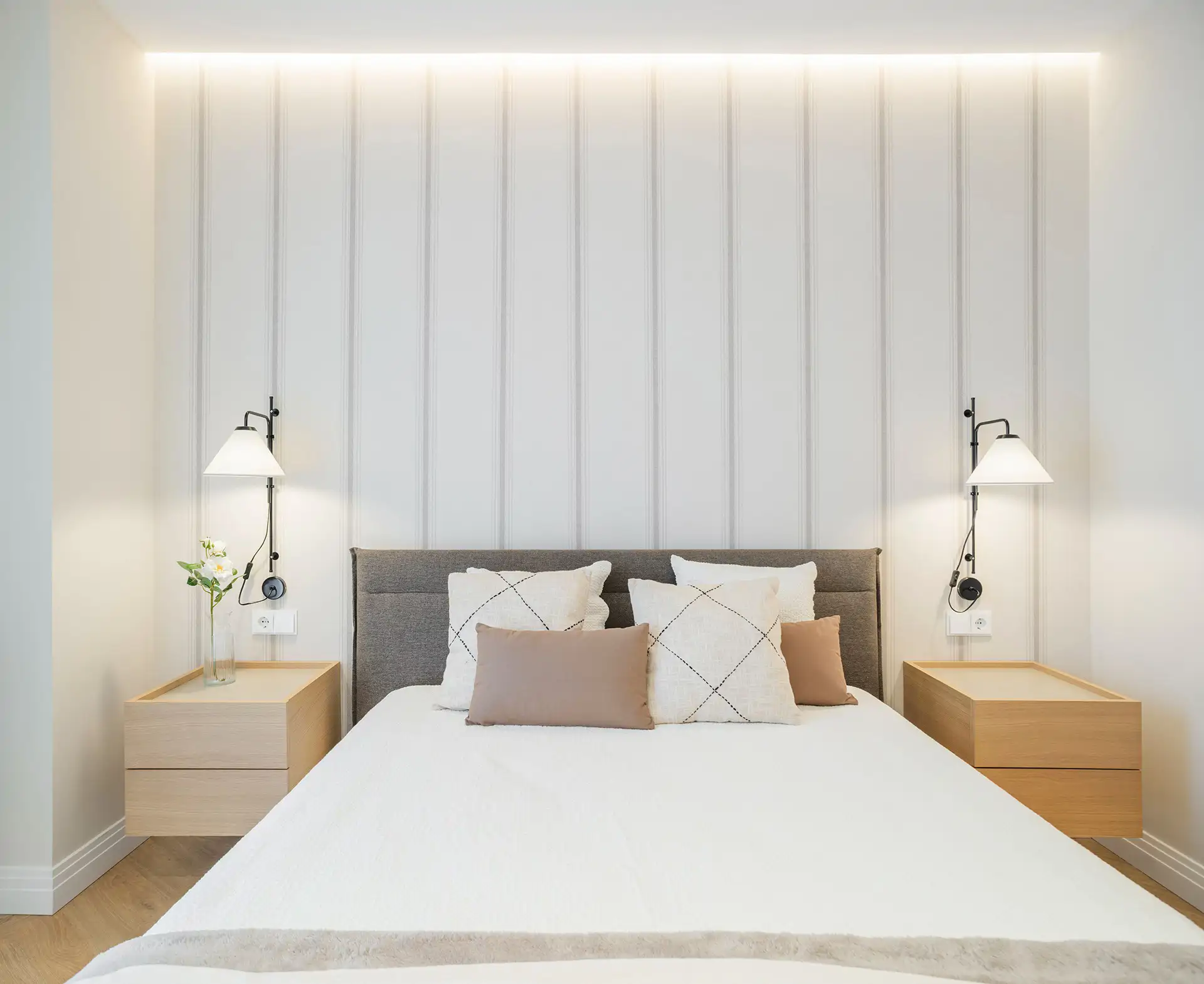 Chambre minimaliste avec appliques murales noires et papier peint à rayures verticales