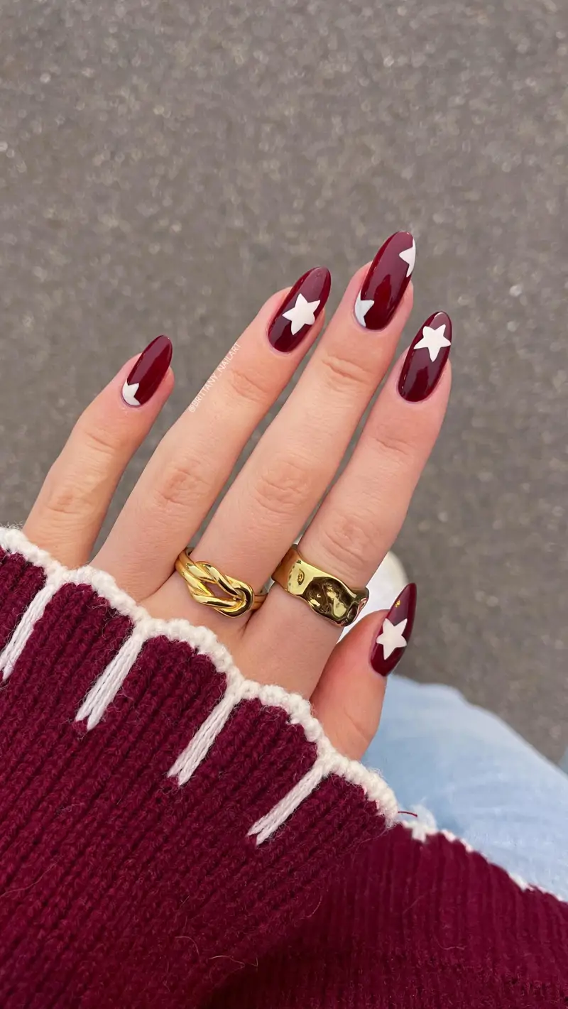 Manucure rouge foncé avec étoiles blanches : nail art délicat et original